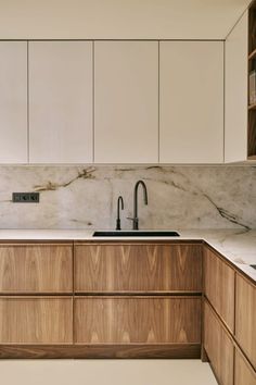 a kitchen with marble counter tops and wooden cabinets, along with a sink that has no faucet