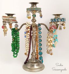 an assortment of beaded bracelets and necklaces hanging from a candelabra