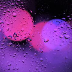 two red and blue circles sitting on top of a purple surface covered in raindrops