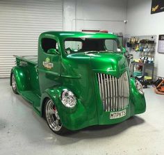 an old green truck parked in a garage