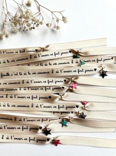 five pieces of ribbon with writing on them next to some small white flowers and branches