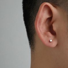 a close up of a man's ear with a single diamond in the middle