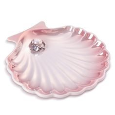 a pink shell shaped dish with a pearl in the center and a ring on it