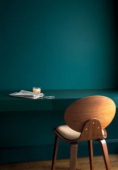 a wooden chair sitting in front of a green wall with a tray on the table