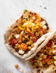 two pita breads filled with vegetables on top of a white countertop next to each other