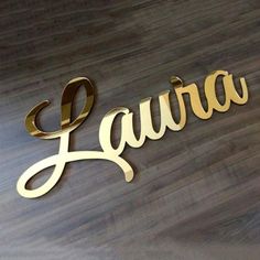 the name laura is made out of gold plating on a wood floor with a black background