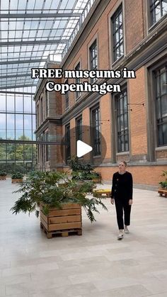 a woman standing in front of a building with plants inside it and the words free museum in copenhagen