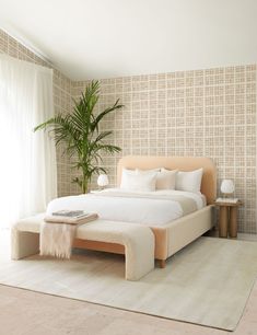 a bedroom with a bed, plant and rug