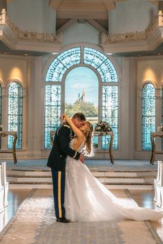 a bride and groom kissing in front of stained glass windows