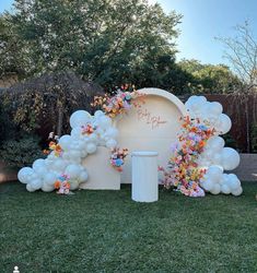 balloons and flowers decorate the entrance to an outdoor wedding ceremony in front of a fence