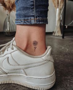 a woman's foot with a small flower tattoo on her left side ribcage