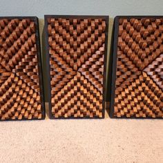 three pieces of wood sitting on top of a floor next to each other in front of a wall