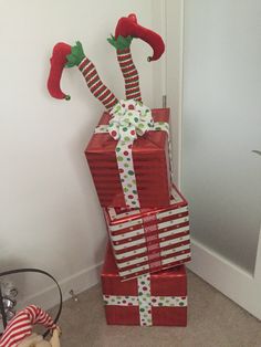 a stack of wrapped presents sitting on the floor next to a christmas hat and candy cane