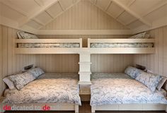 two bunk beds in a room with white walls and wood paneling on the ceiling