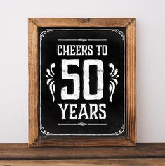 a black and white sign that says cheers to 50 years on the side of a wooden frame