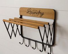 a wall mounted coat rack with three coats hanging from it's sides and two hooks on each side