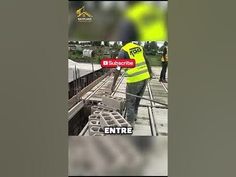 a man in yellow vest standing on top of a train track next to a sign