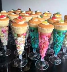 there are many cupcakes with candy in them on the glass cups and one is filled with candies