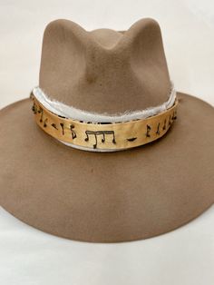 Hand embroidered hat band with musical notes embroidered along length. Band is a golden yellow color with dark gray embroidery and is reversible. Alternate side is a tan/brown basic fabric. Gold Wide Brim Fedora For Festivals, Gold Fedora Western Hat, Gold Western Fedora Hat, Western Style Gold Fedora With Flat Brim, Western Style Gold Fedora With Short Brim, Western Gold Fedora With Short Brim, Gold Fedora With Short Brim For Festivals, Adjustable Gold Wide Brim Fedora, Adjustable Gold Fedora For Festivals