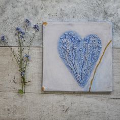 two blue flowers are sitting next to a heart shaped tile