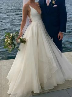 a bride and groom posing for a photo in front of the water