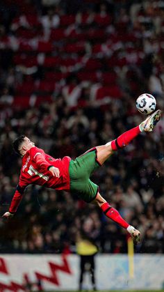 a man kicking a soccer ball in the air with his legs stretched out to catch it