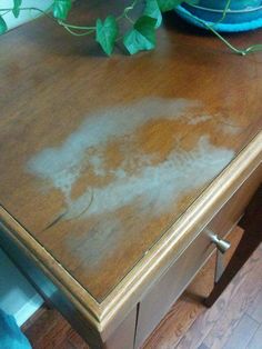 a brown table with white stains on it next to a potted plant