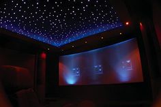 the ceiling is covered in blue lights and there are two people watching movies on the screen