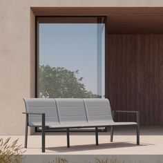 a white bench sitting in front of a window on the side of a building next to plants