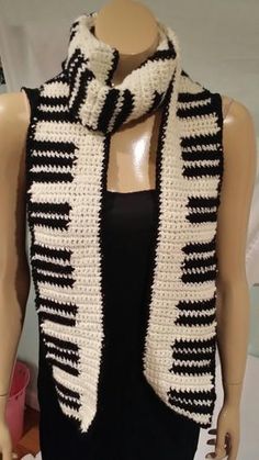 a mannequin wearing a black and white knitted scarf on top of a table