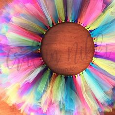 a multicolored tulle wreath on top of a wooden table