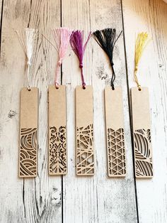 four wooden bookmarks with tassels and thread in them sitting on a table