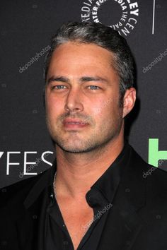 a man with grey hair and black shirt posing for the camera in front of a black background