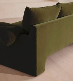 a green couch sitting on top of a hard wood floor