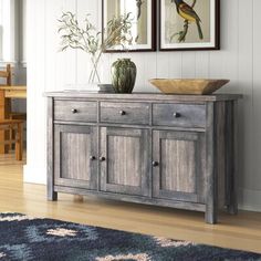 a wooden cabinet with two pictures on the wall above it and a rug in front of it