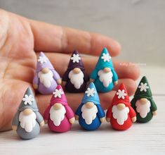 a hand is holding seven small gnomes in different colors