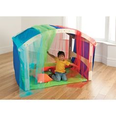 a young boy is playing in a play house made out of plastic sheets and mesh