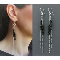 a pair of black and silver earrings with chains hanging from the back, on top of a woman's head