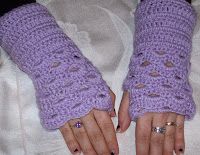 the woman is wearing purple crocheted gloves with holes on them and her hands