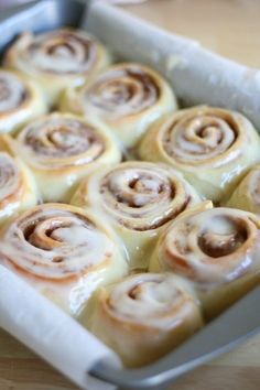 a pan filled with cinnamon rolls sitting on top of a wooden table