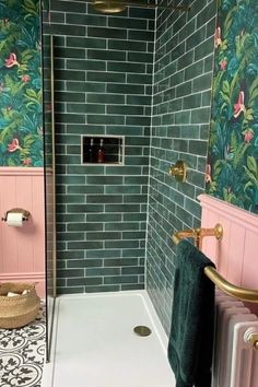 a pink and green tiled bathroom with gold faucet, shower head, and towel rack