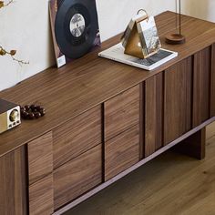 a record player sitting on top of a wooden cabinet next to a wall mounted clock