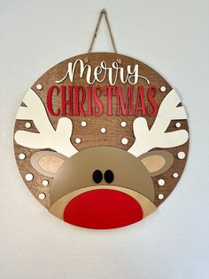 a merry christmas sign hanging from the side of a wall with reindeer's head on it