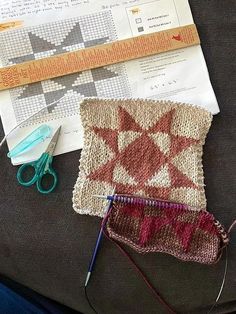 a pair of scissors and some knitting material on top of a piece of cloth with crochet needles