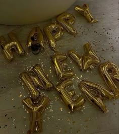 gold foil balloons spelling out the word happy birthday in front of a white bathtub