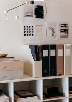 several books are stacked on top of each other in front of a wall with pictures