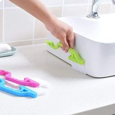 a person is cleaning the counter top with two toothbrushes and a scrubber