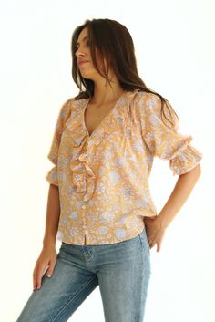 Discover our Chloe Shirt. Ethically made from a sustainable soft cotton orange and white floral print, she exudes comfort and style. Designed as a voluminous blouse, she features timeless, feminine details such as a ruffle neckline, real shell buttons, and petit pin-tucks. A true closet staple, the Chloe Shirt can be styled from day to night all year long. Responsibly Handcrafted by women artisans using high-quality sustainable fabrics certified Oeko Tex Standard 100.1% of your order funds regen Soft Feminine Style, Poppy Garden, Feminine Details, Closet Staples, Shell Buttons, Women Artisans, Sustainable Fabrics, Pin Tucks, Poppies