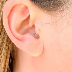 a close up of a person's ear with a small gold ring on it