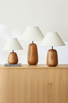 three wooden lamps sitting on top of a dresser